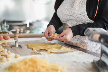 Senior woman doing fresh made ravioli inside pasta factory