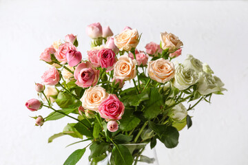 Vase with bouquet of beautiful roses on light background