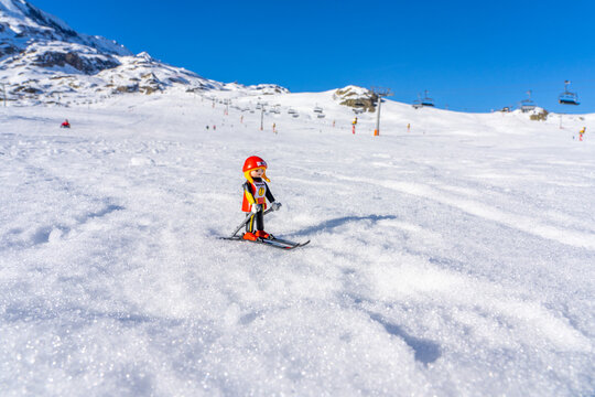Alpes d'Huez, France - 01.01.2022: Lego plastic toy skier on the real ski french resort, winter snow mountains background. High quality photo