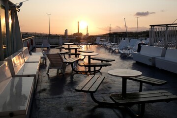Restaurant tables on outer deck of passenger ship at sunset.