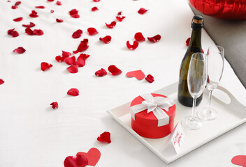 Tray with gift for Valentine's Day and champagne on bed in morning