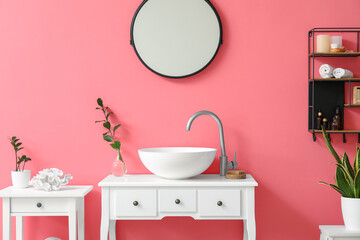 Interior of stylish bathroom with sink, mirror and pink wall