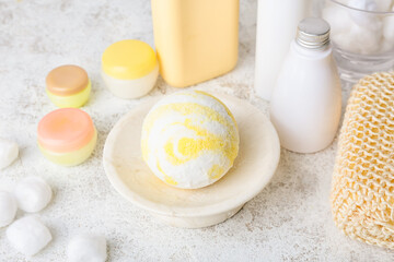 Bowl with bath bomb, cosmetics and cotton balls on light background, closeup