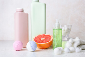 Fototapeta na wymiar Different bath supplies and grapefruit on light background