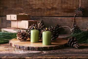 Board with burning candles and pine cones on wooden table