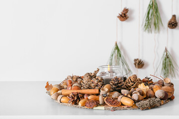 Composition with burning candle and pine cones on table in room