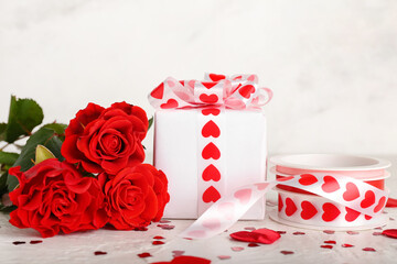 Gift for Valentine's Day and roses on light background