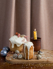Kulichi, a traditional Russian Easter cake with icing and a candle on a wooden background