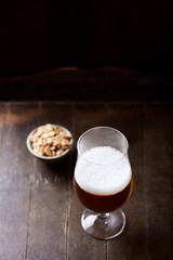 Glass of beer on dark wooden background. Copy space.