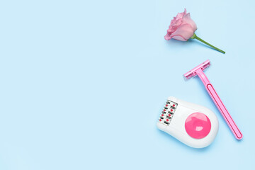 Modern epilator, flower and razor on blue background