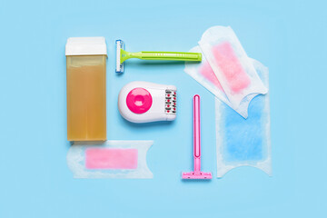 Different supplies for hair removal with modern epilator on blue background