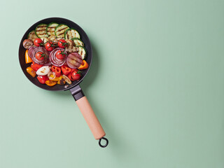 variety of vegetables grilled in a cast iron pan with a wooden handle. Zucchini, red onion; red, orange and yellow peppers, eggplant and cherry tomatoes. 