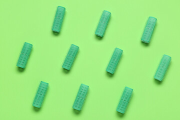 Set of hair curlers on green background