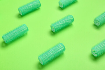 Set of hair curlers on green background