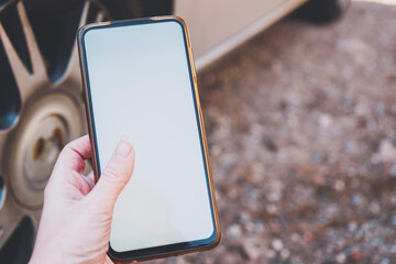 Hand holding an android smart phone near a car