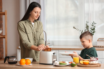 Little boy with his mother making tasty toasts in kitchen