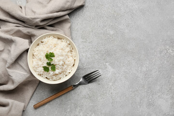 Bowl with tasty boiled rice on grey background