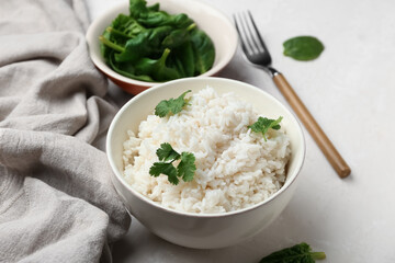 Bowl with tasty boiled rice and spinach on light background, closeup