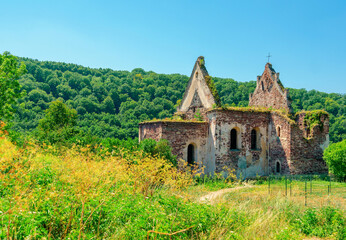 Destroyed stone medieval church in the green forest. Desolation. The spirit of the ages.