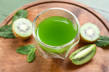 Glass of healthy green juice and fresh kiwi on table