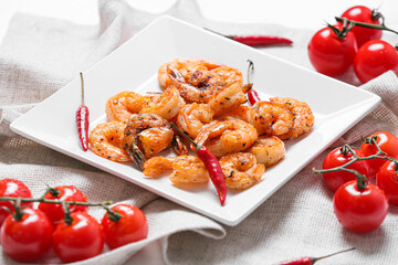 Plate of tasty shrimp tails with tomatoes on table