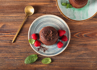 Plates with tasty lava cake fondant and raspberry on wooden background
