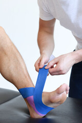 Kinesiology taping treatment with blue tape on male patient injured foot. Sports injury kinesio...