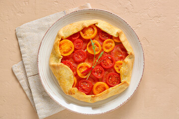 Plate with tasty tomato galette on beige background
