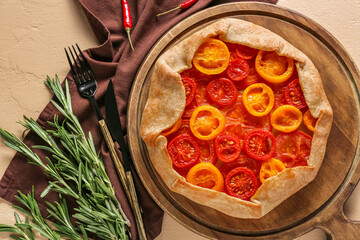 Board with tasty tomato galette and spices on beige background