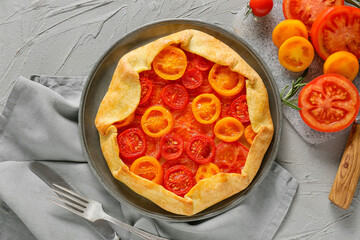 Plate with tasty tomato galette on grey background
