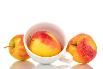 Three red juicy apples with a white ceramic cup, macro, isolated on white.