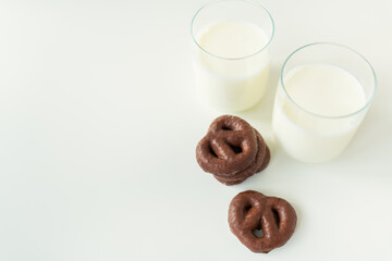 Gingerbread cookies in chocolate lie on a white table along with a glass of milk. Place for an inscription.