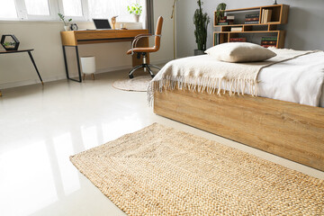 Stylish wicker rug on floor in modern bedroom