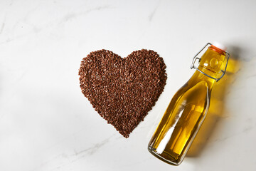 Top view of flaxseed formed into a heart shape next to a bottle of fish oil