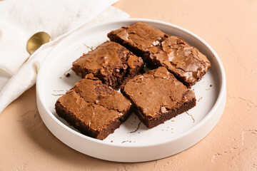 Plate with pieces of tasty chocolate brownie on beige background