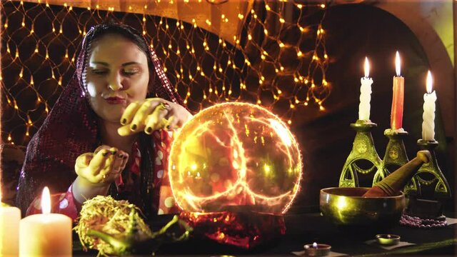 A young sorceress is engaged in magic, reading fate from a small ball by candlelight.