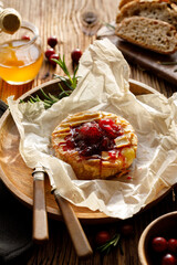 Baked camembert cheese served with the addition of cranberry jam, close up view.