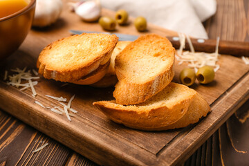 Board of tasty croutons with cheese on table, closeup