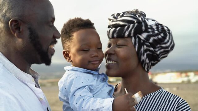 Happy African family having fun on the beach during summer holidays - Parents love concept