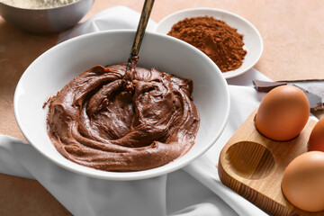 Bowl with fresh dough for preparing chocolate brownie on table