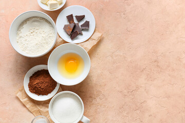 Bowl with flour and ingredients for preparing chocolate brownie on beige background