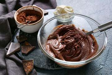 Bowl with fresh dough for preparing chocolate brownie on black background