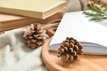 Opened book and pine cones on soft plaid, closeup