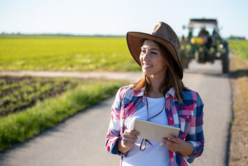 Farmer woman with tablet in front of tractor