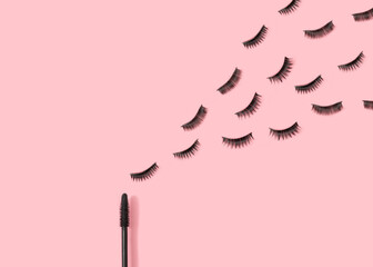 Eyelashes and mascara brush on pastel pink background. Creative makeup concept. Minimal beauty aesthetic. Flat lay.