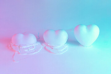 Three hearts on powder texture with neon purple violet and blue lights. Minimal love concept....