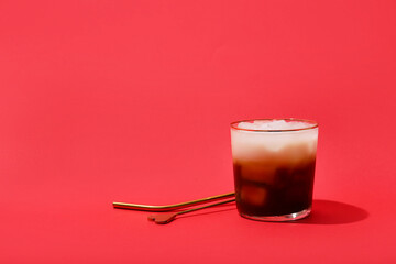 Glass of White Russian cocktail on red background
