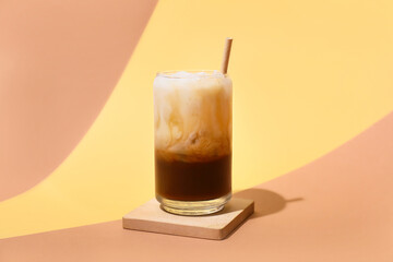 Glass of White Russian cocktail on yellow background