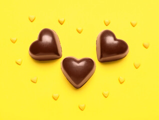 Tasty heart-shaped candies on yellow background