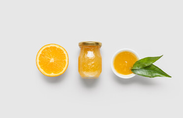 Composition with tasty orange jam and leaves on light background